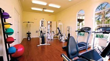 a gym with cardio equipment and weights on a wooden floor